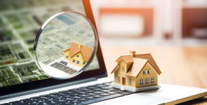 Miniature house on a laptop indicating researching property before purchasing.