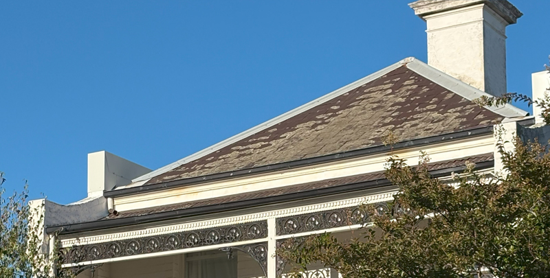 Melbourne terrace house with chimney and slate roof with a blue sky background