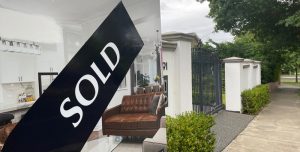 A for sale board on the front fence of a property with a sold sticker applied